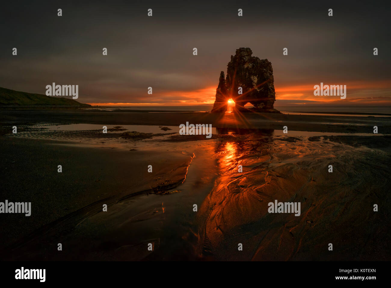 Rosso tramonto su Hvitserkur rock sulla spiaggia nera, Islanda Foto Stock