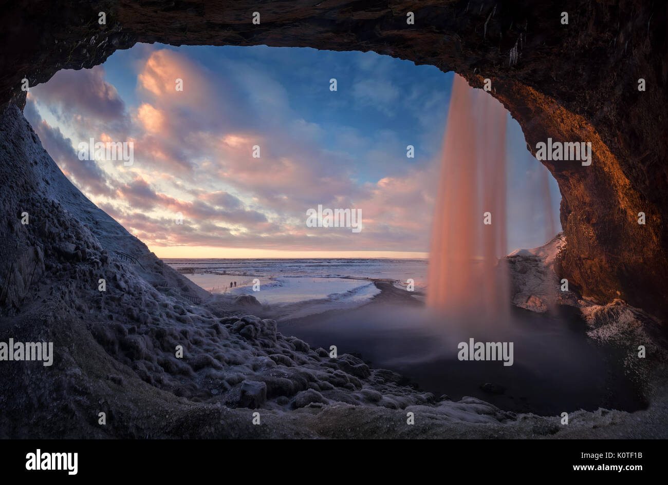 Tramonto colorato nella grotta dietro la cascata Seljalandsfoss in inverno, Islanda Foto Stock