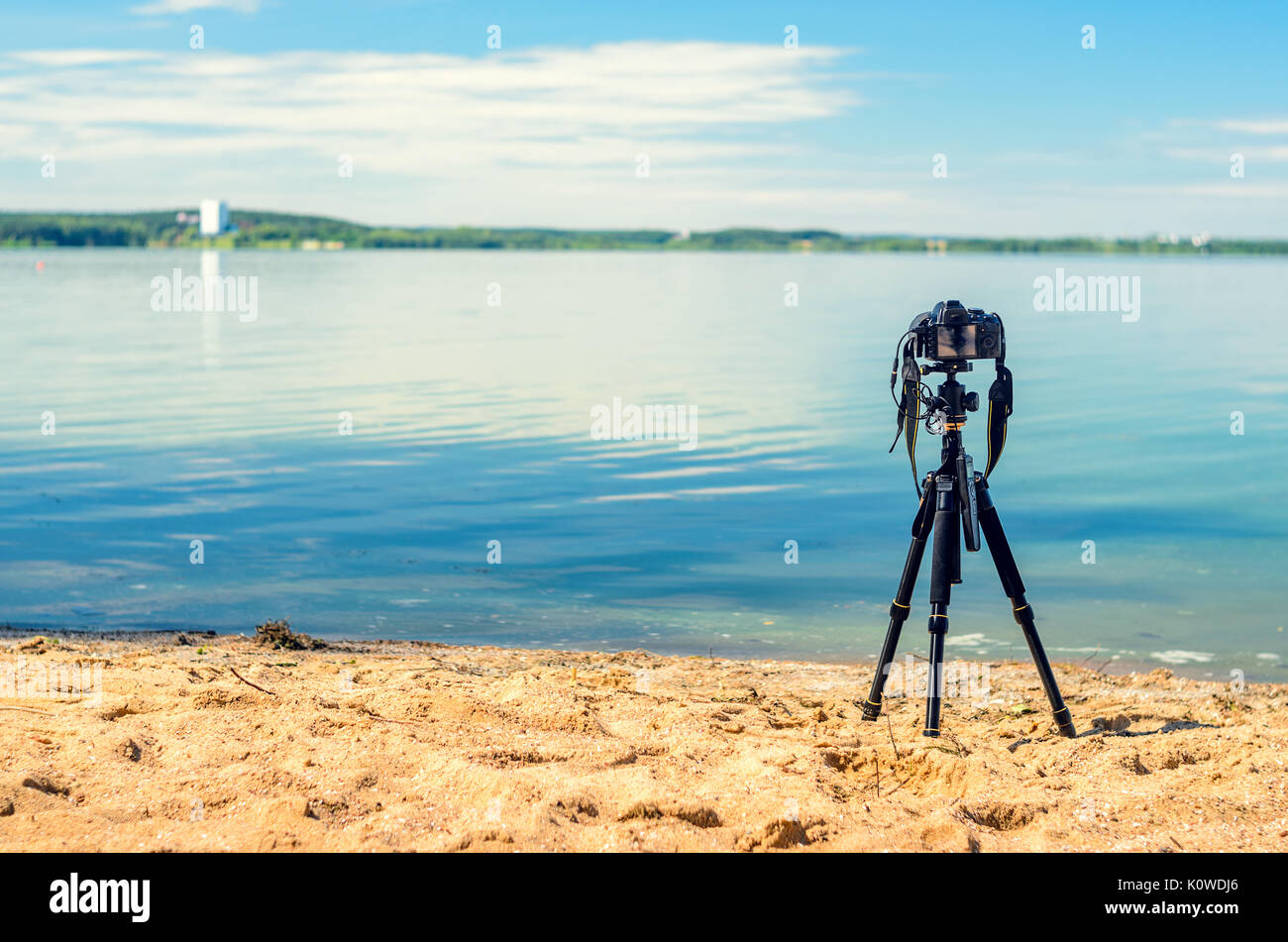 Una telecamera su un treppiede sulla spiaggia sabbiosa rimuove il seascape. Attrezzature fotografiche nel processo di ripresa del paesaggio. Fotocamera mentre prendendo Foto Stock