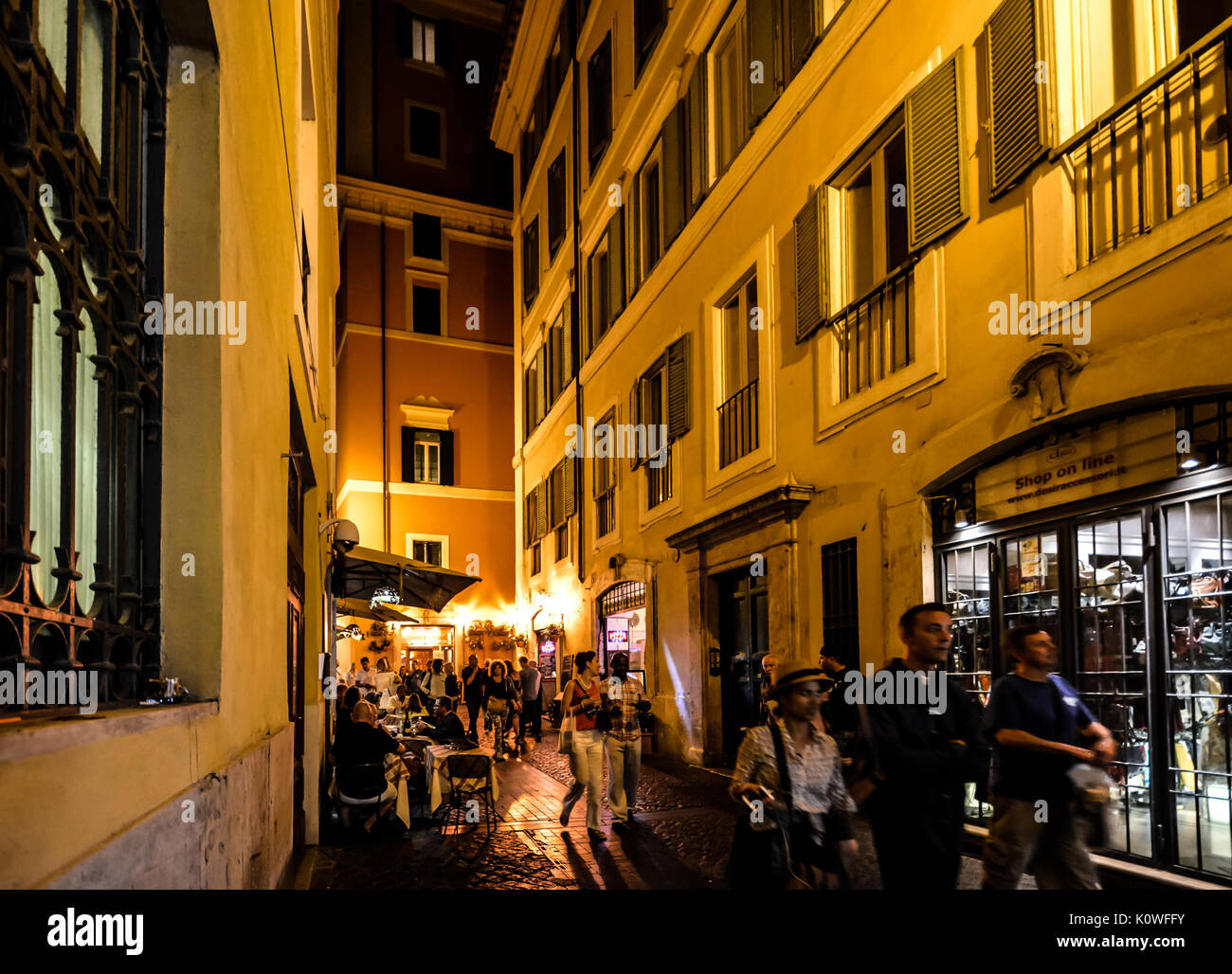 Una passeggiata serale a Roma Italia attraverso una stretta strada sul retro con un cafe' all'aperto e di turisti che si diverte Foto Stock