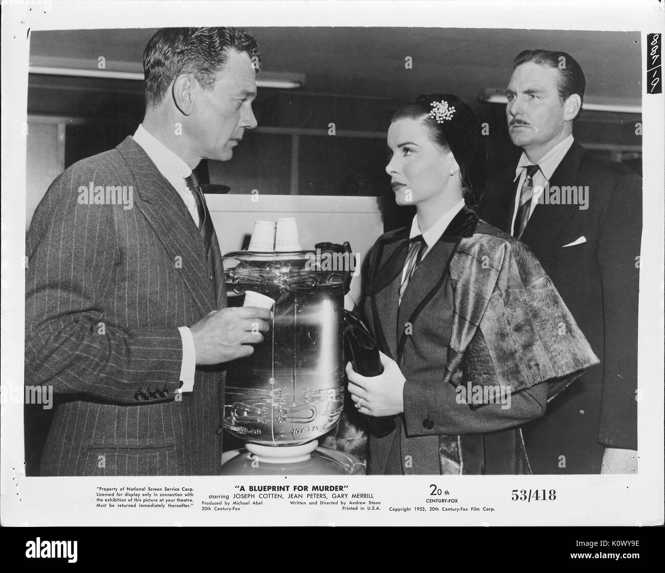 Un film scena ancora da 'un blueprint per omicidio" (1953 XX Century Fox Film thriller), che mostra un uomo in striped abito scuro ordina di mettere in discussione un ben vestito lady mentre l'uomo con un baffi in abito scuro dietro di lei guarda con un cipiglio, 1953. Foto Stock