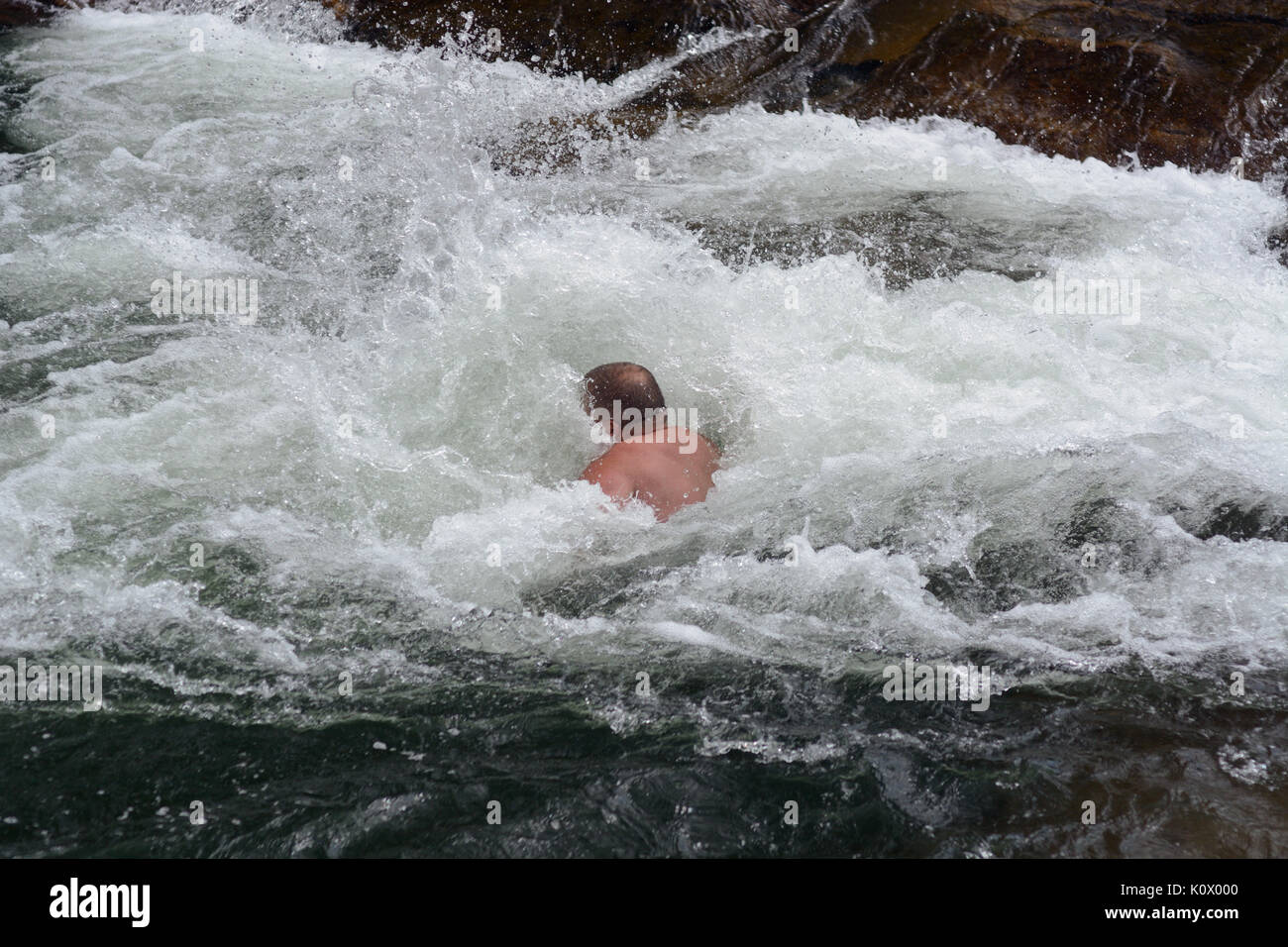 L'uomo quasi completamente sommerso in acqua bianca rapids dopo immersione in acqua Foto Stock