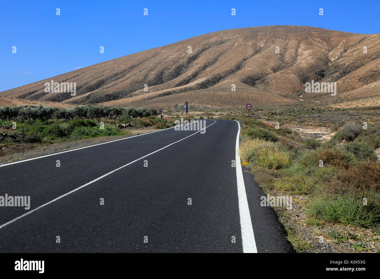 Su strada asfaltata attraversando il deserto, Fuerteventura, vicino a Pajara, Isole Canarie, Spagna Foto Stock