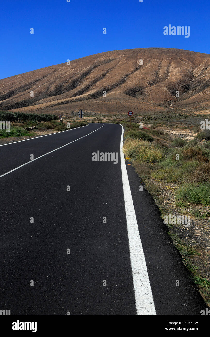 Su strada asfaltata attraversando il deserto, Fuerteventura, vicino a Pajara, Isole Canarie, Spagna Foto Stock