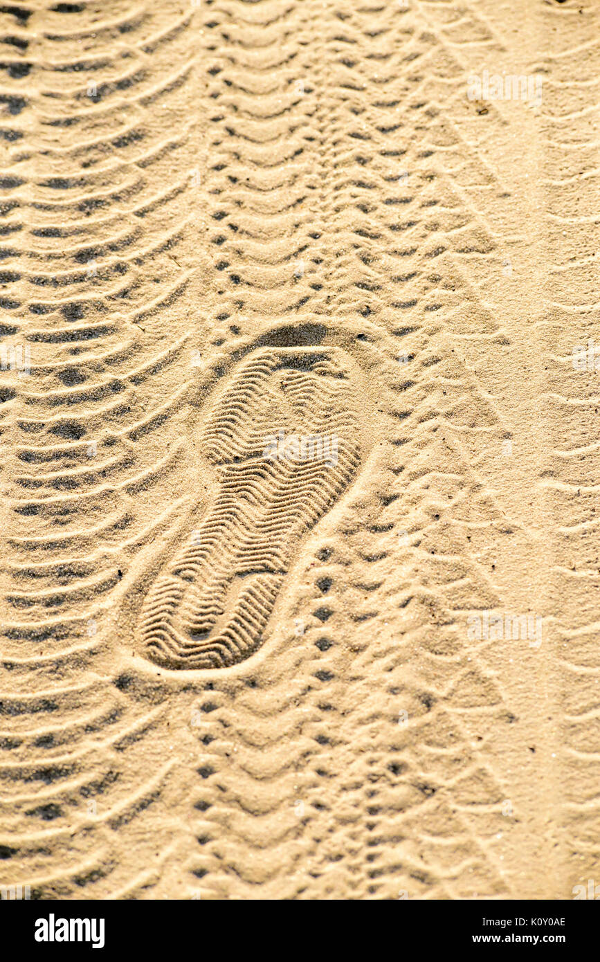 Auto piste, piste ciclabili e stampe di calzatura nella sabbia illuminato dal basso sera raggi di sole Foto Stock