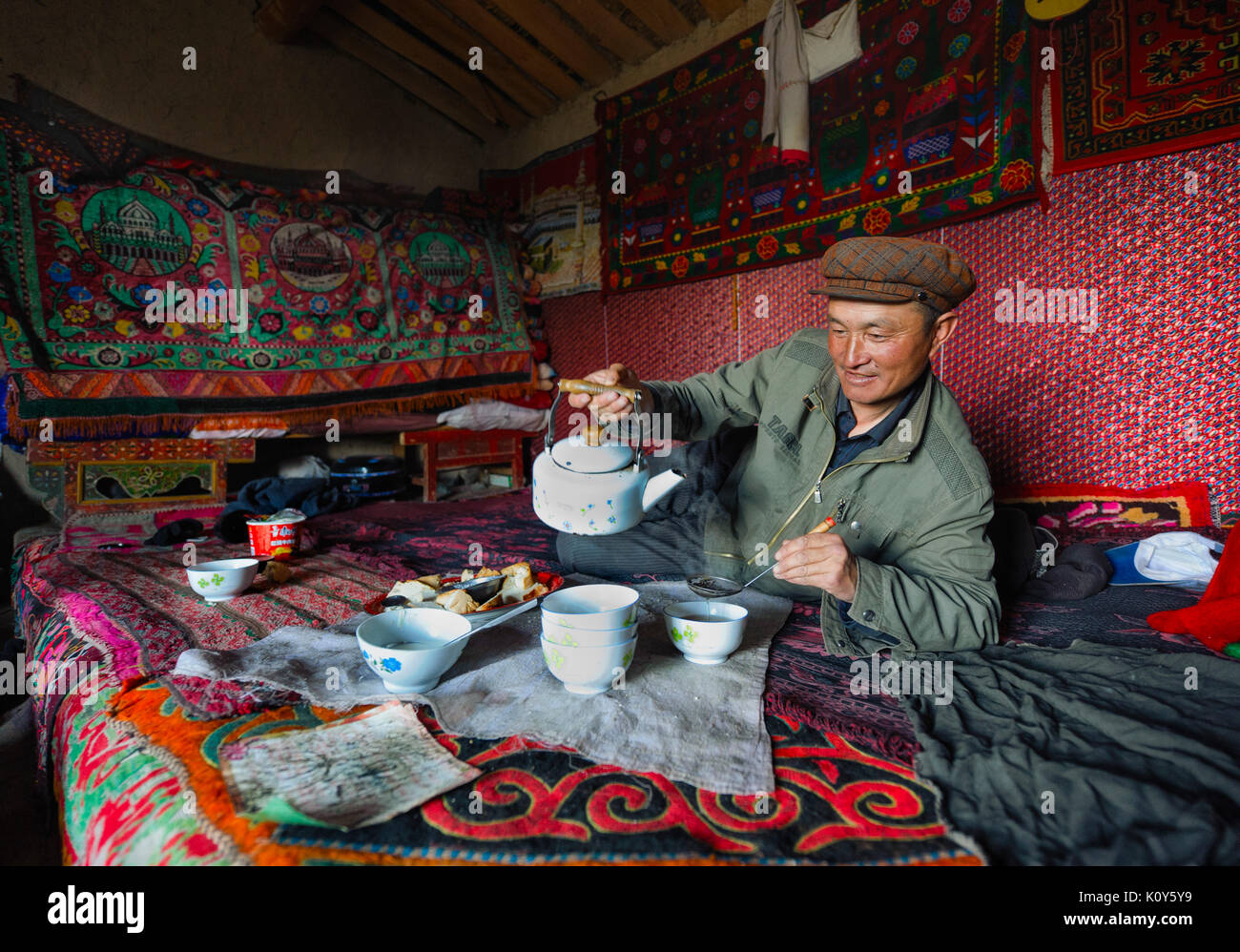 Un Uighur uomo in appoggio e a pranzo a mezzogiorno in remoto di Xinjiang Foto Stock