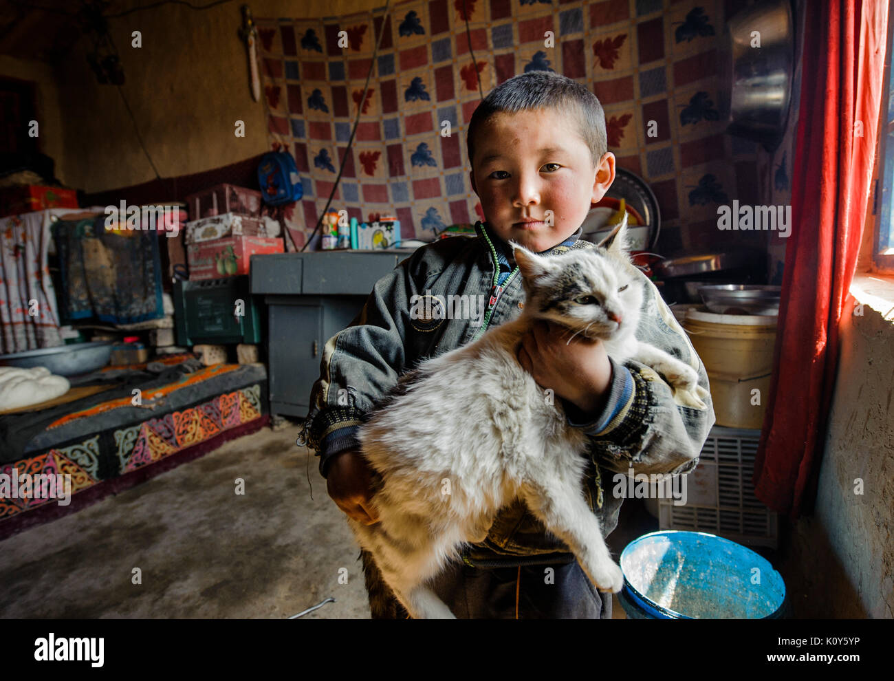Un Uighur kid e il suo gatto. Remote Xinjiang Foto Stock