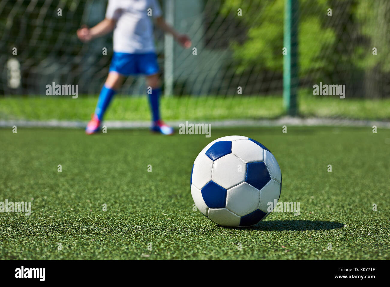 Pallone da calcio sul prato verde dello stadio e il ragazzo di calcio al gate keeper Foto Stock