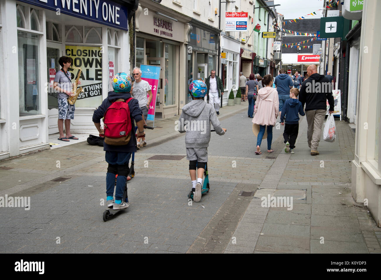West Wales. Haverford West. Bridge Street. Bambini su scooter. Foto Stock
