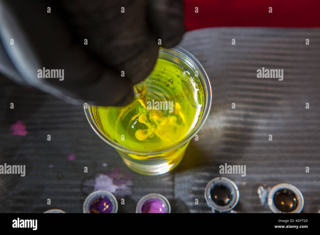 Tattoo Artist pulizia della macchina ago dell'acqua dopo l'uso di colore giallo. Primo piano Foto Stock