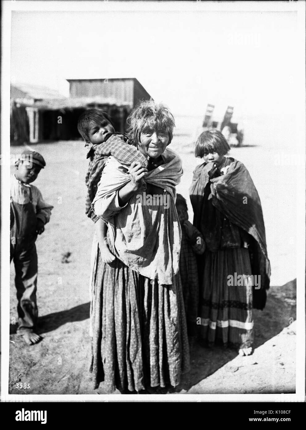 Apache Indian nonna portando la sua nipote sulla sua schiena e gli altri due in piedi nelle vicinanze, Palomas Indian Reservation, 1903 (CHS 3585] Foto Stock
