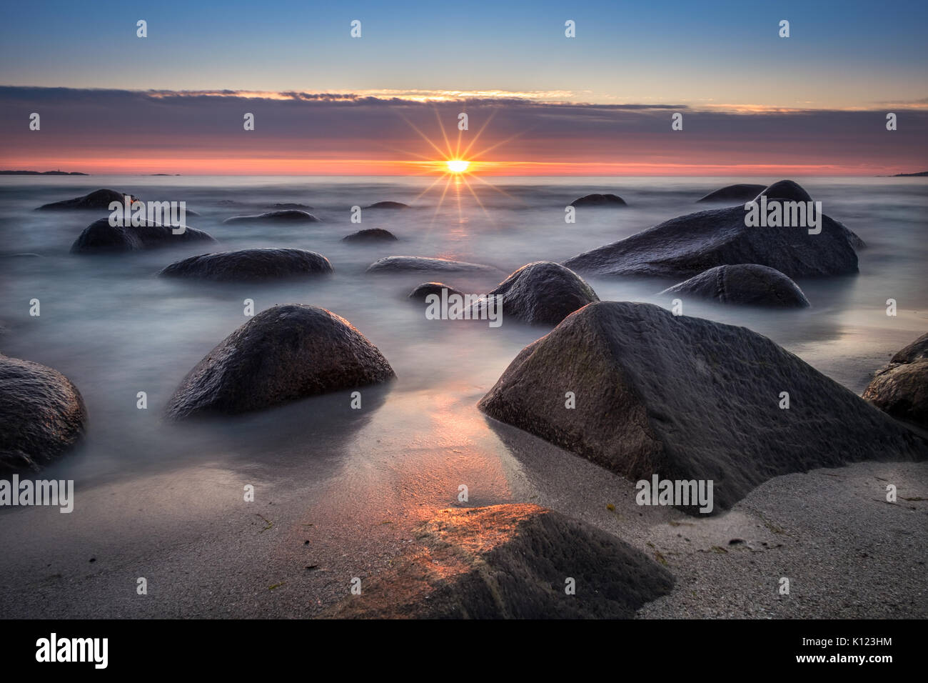 Vista panoramica dalla spiaggia con pietre e tramonto a notte estiva in Lofoten, Norvegia Foto Stock