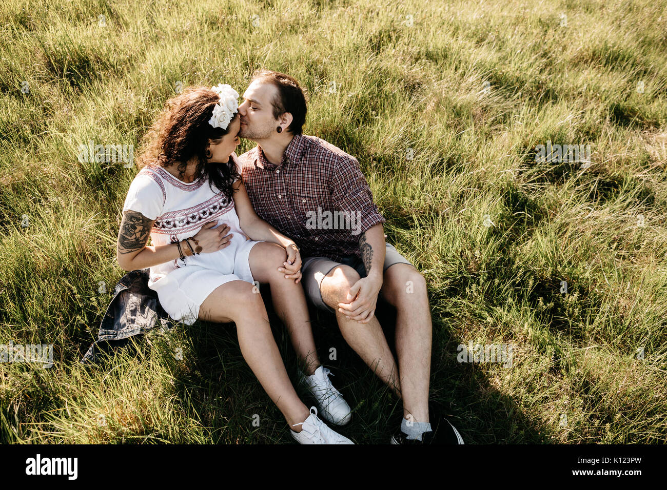 Ritratto di un amorevole incinta giovane seduto sull'erba Foto Stock