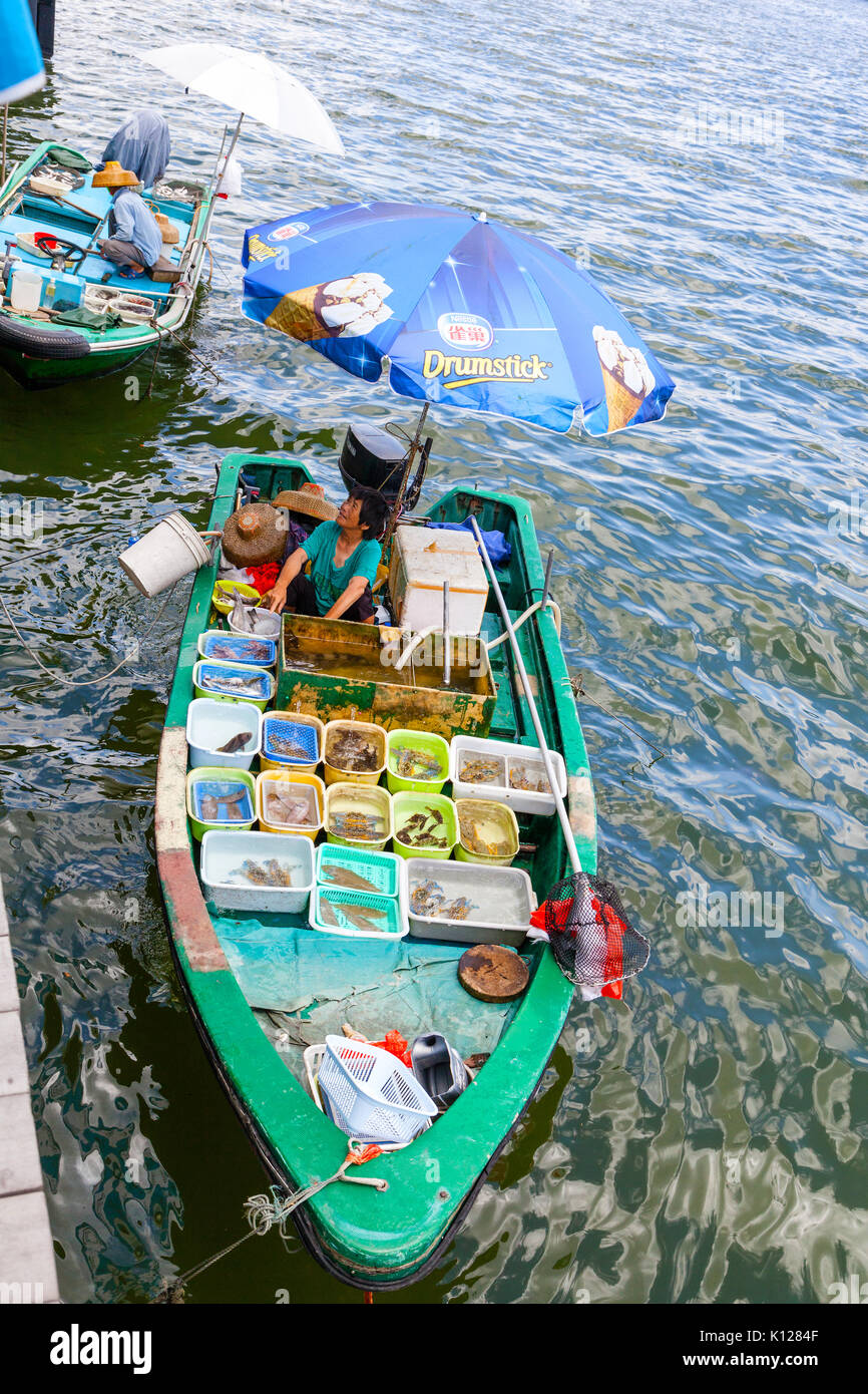 HONG KONG - Luglio 13, 2017: un pescatore separa il suo live di cattura di pesce in contenitori di plastica su una barca a Sai Kung il flottante sul mercato di frutti di mare. Fishe Foto Stock