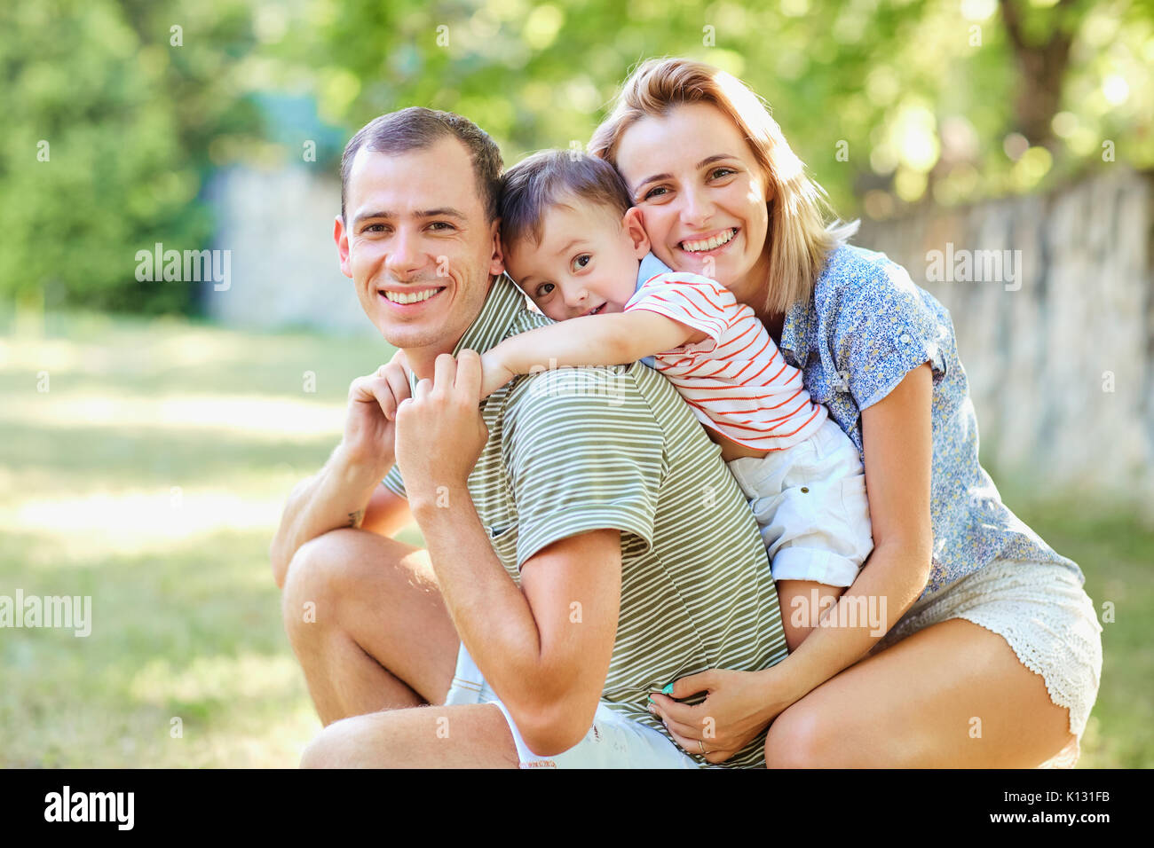 La famiglia felice sorridente giocando in estate park. Foto Stock