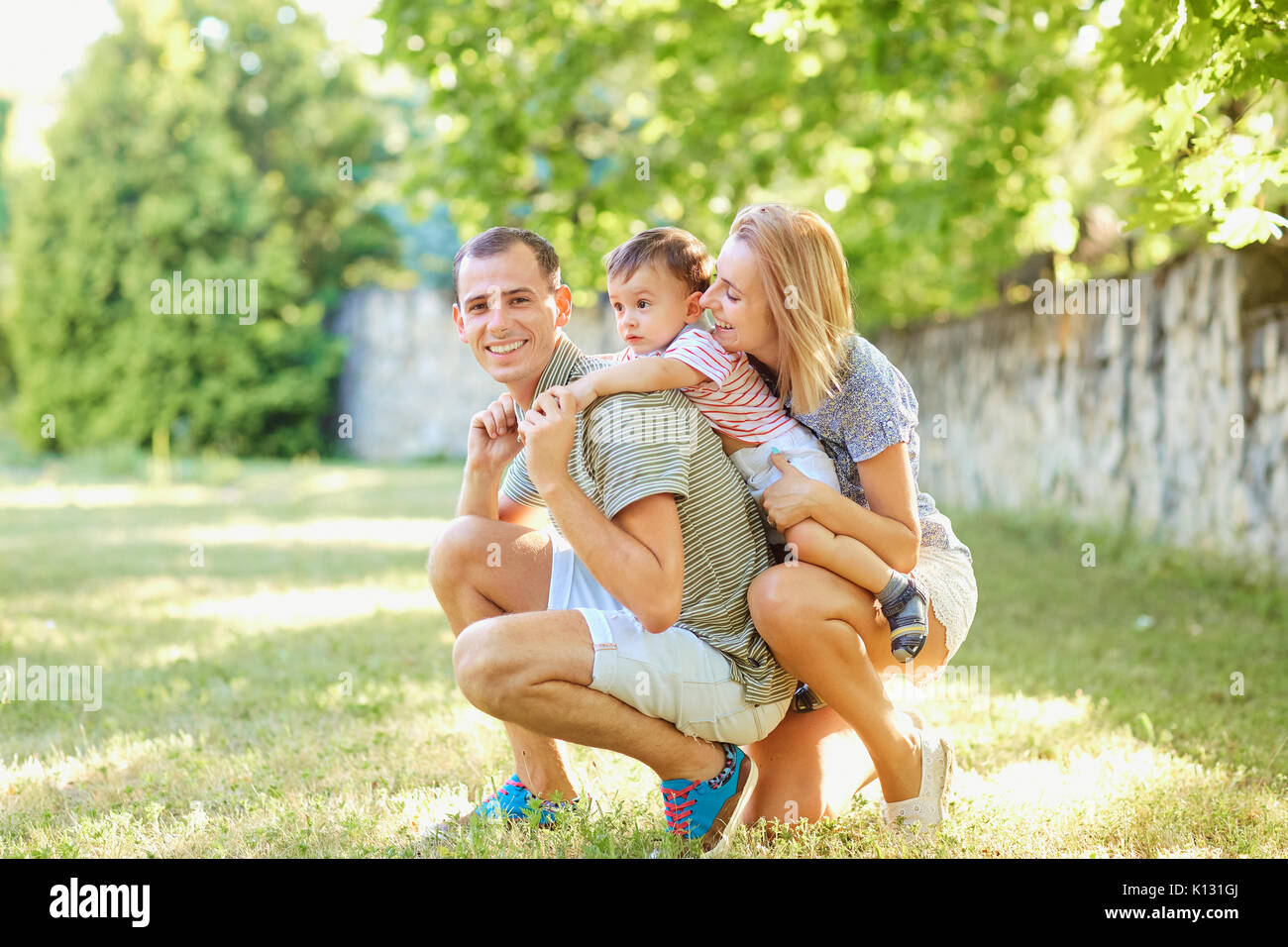 La famiglia felice sorridente giocando in estate park. Foto Stock