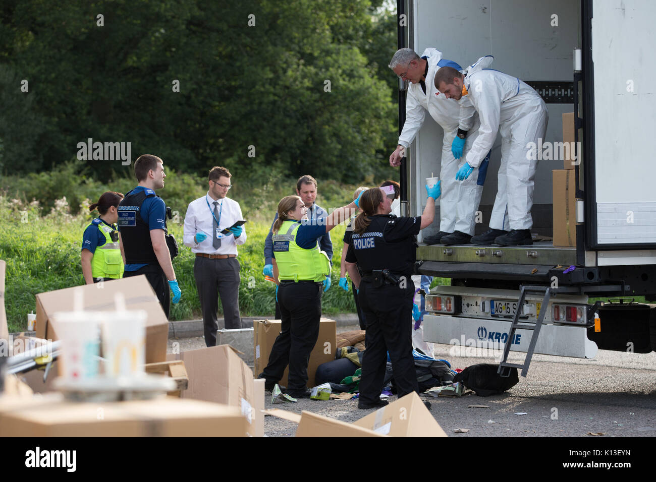 Gli ufficiali di polizia e squadre di ricerca vai attraverso le scatole trovati in un autocarro dove 13 uomini e ragazzi, compreso un 15-anno-vecchio, sono state scoperte al servizio di mangrovie stazione, sulla A45 London Road, nel Rugby Warwickshire. Foto Stock