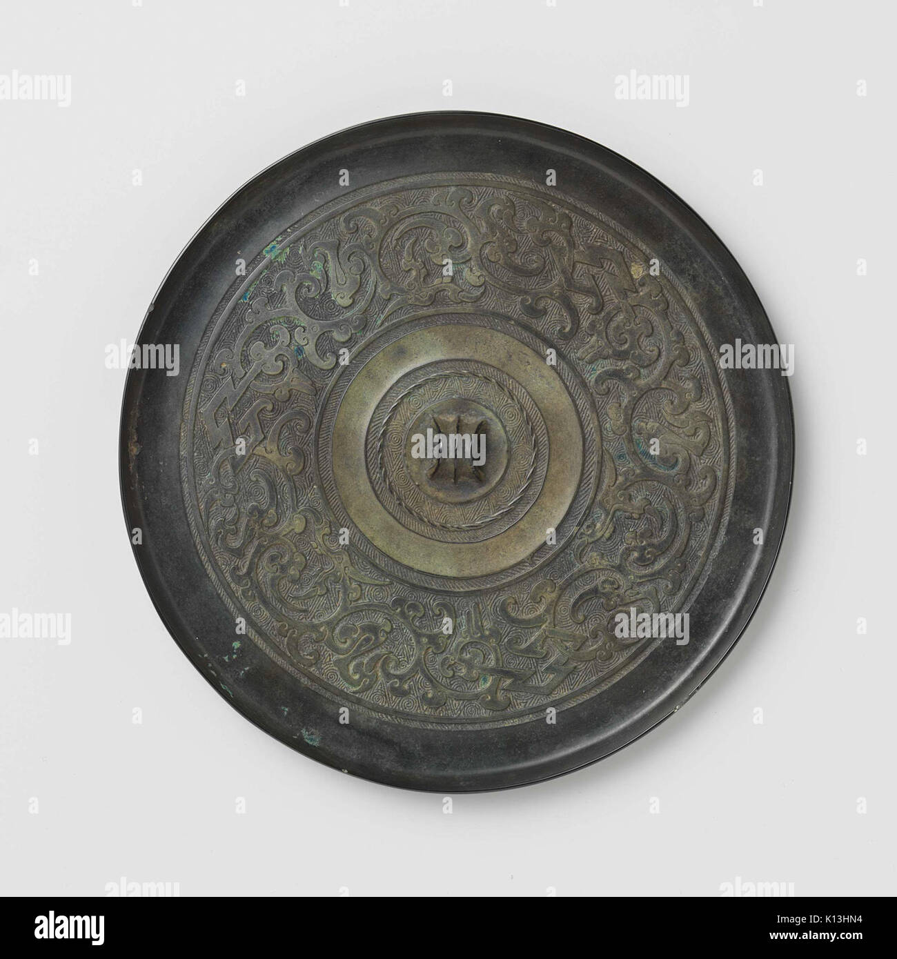 Uno specchio caratterizzato da motivi stilizzati di uccelli e draghi, progettato con motivi intricati e creature mitiche, che combinano arte e artigianato nella sua forma decorativa. Foto Stock