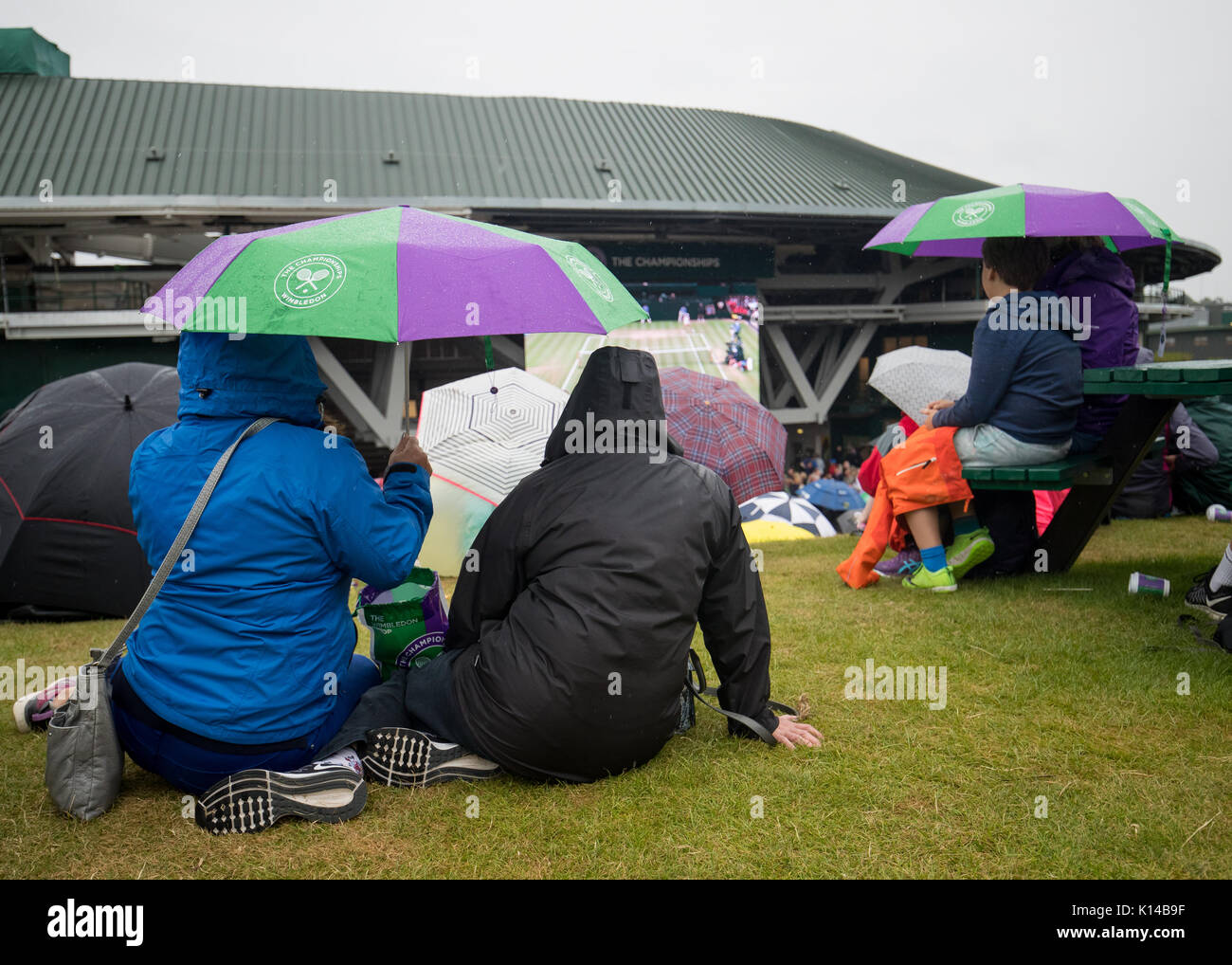 Tifosi guardare il grande schermo da Henman Hill nella pioggia a campionati di Wimbledon 2017 Foto Stock