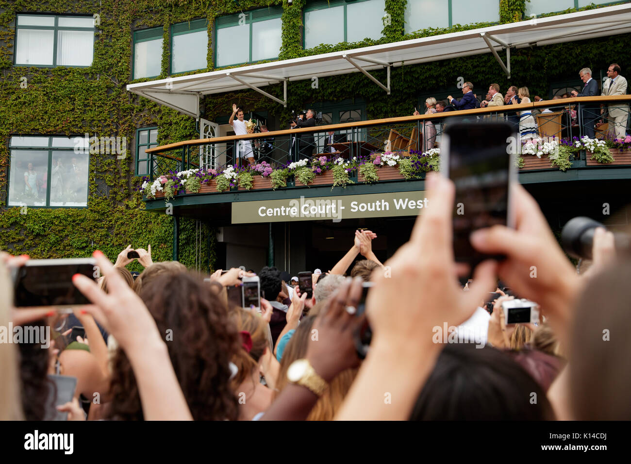 Roger Federer con il suo trofeo sul Centre Court balcone guardato da appassionati al singolo maschile - campionati di Wimbledon 2017 Foto Stock