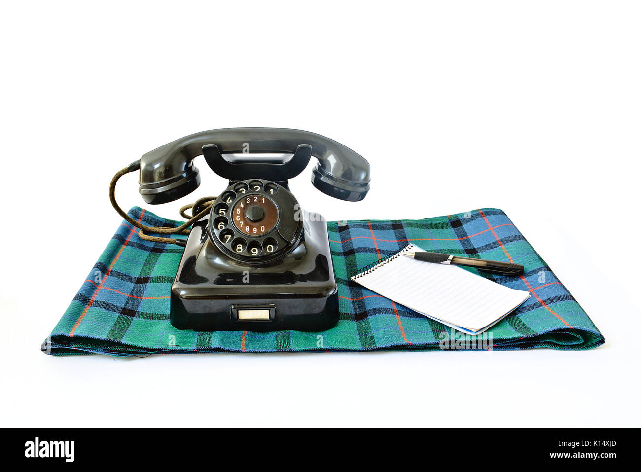 Telefono vintage in tartan plaid con la penna nera e blocco note con copyspace isolato su sfondo bianco Foto Stock