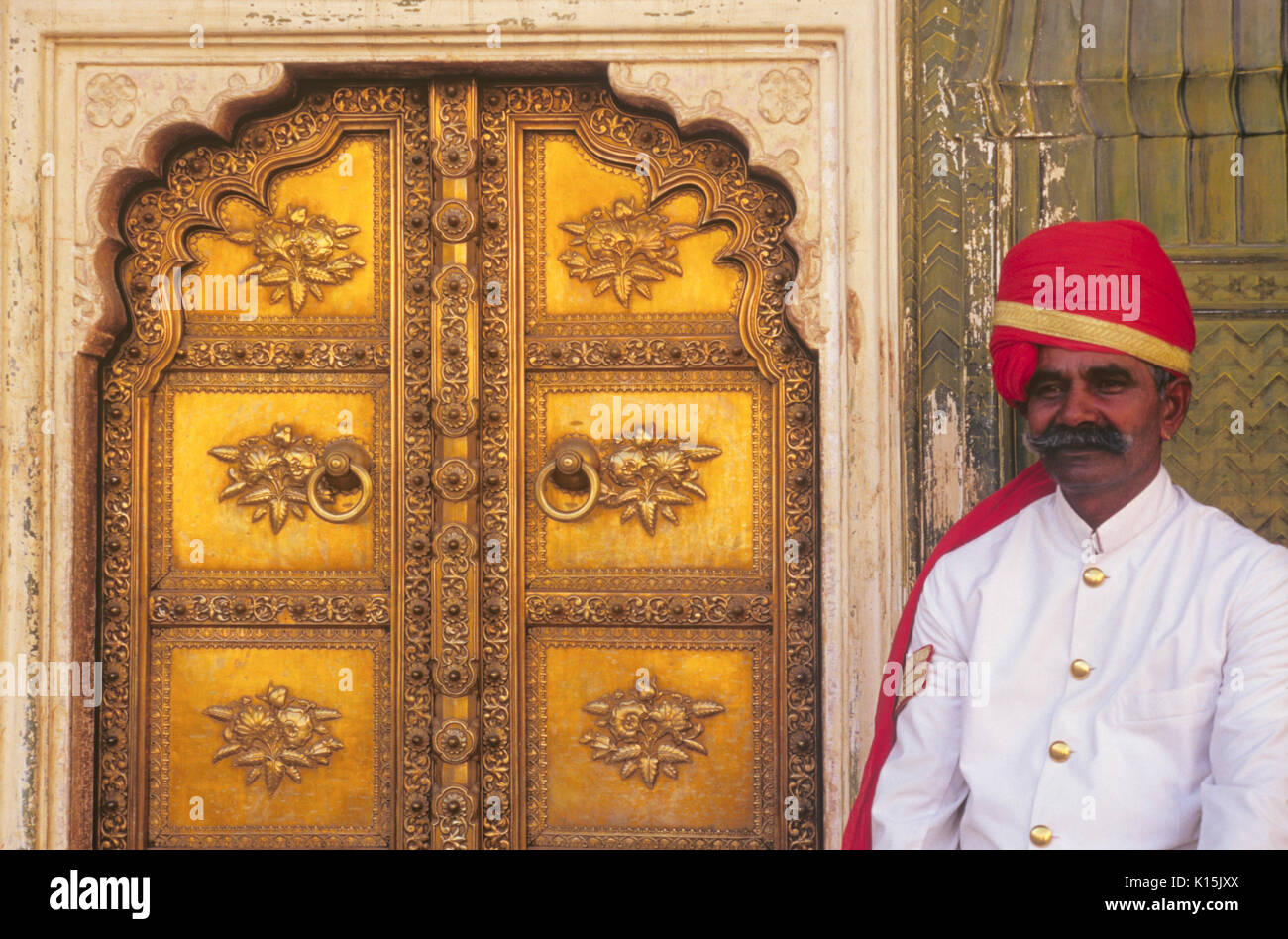 Guard accanto all'ornato oro porta a Mahajara del Palazzo di Città, Jaipur, Rajasthan, India Foto Stock
