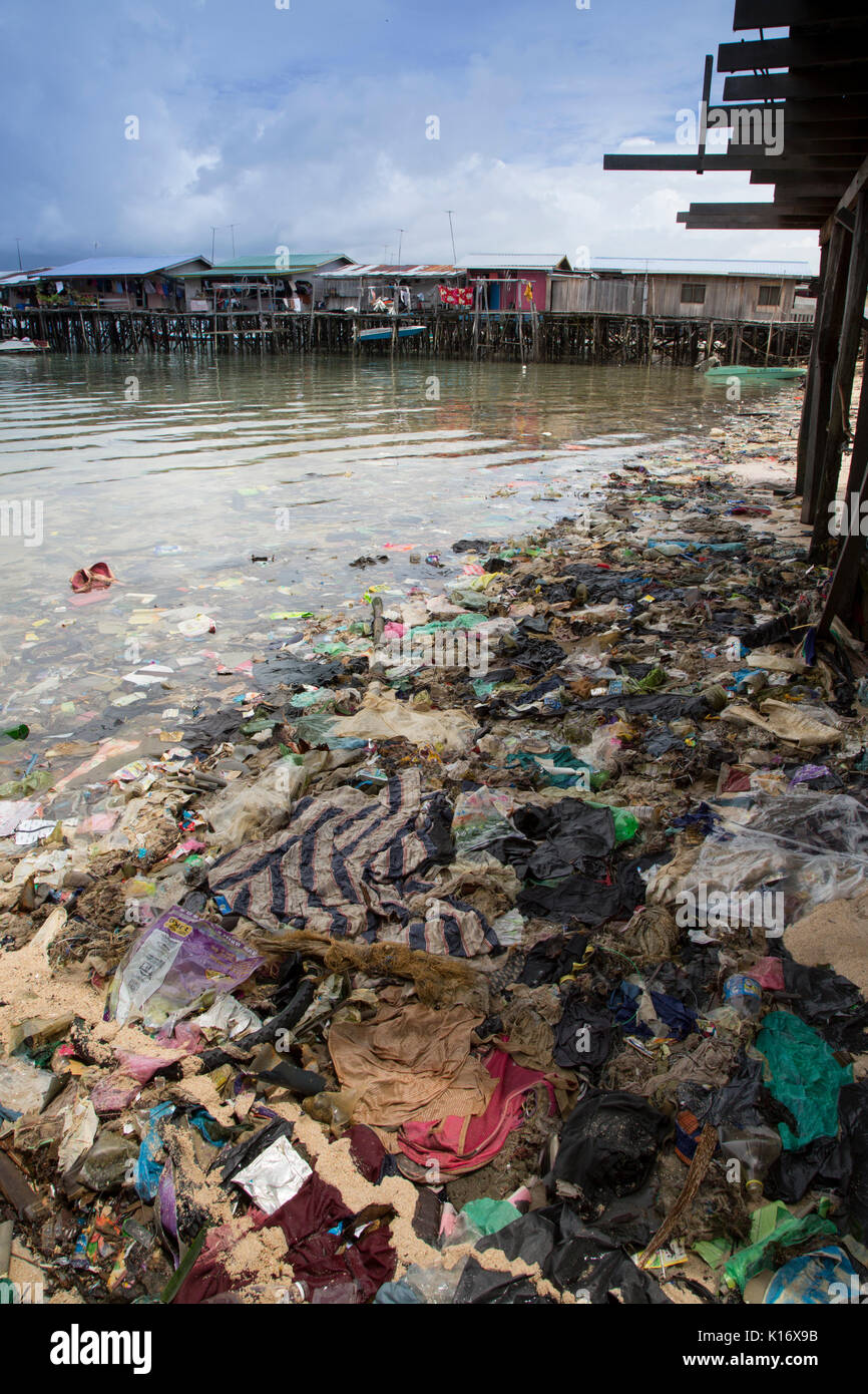 Immondizia di plastica e di altri rifiuti per un brutto spiaggia sulla scena Mabul Isola, Borneo. Le costruzioni in legno su palafitte sono bilancio dive resorts Foto Stock