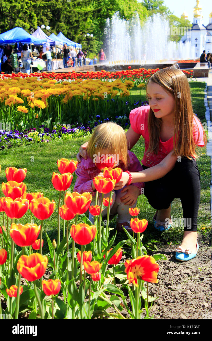 La sorella insegna il giovane di odore tulipani sulla città aiuola. Bambini odore tulip su una città aiuola Foto Stock