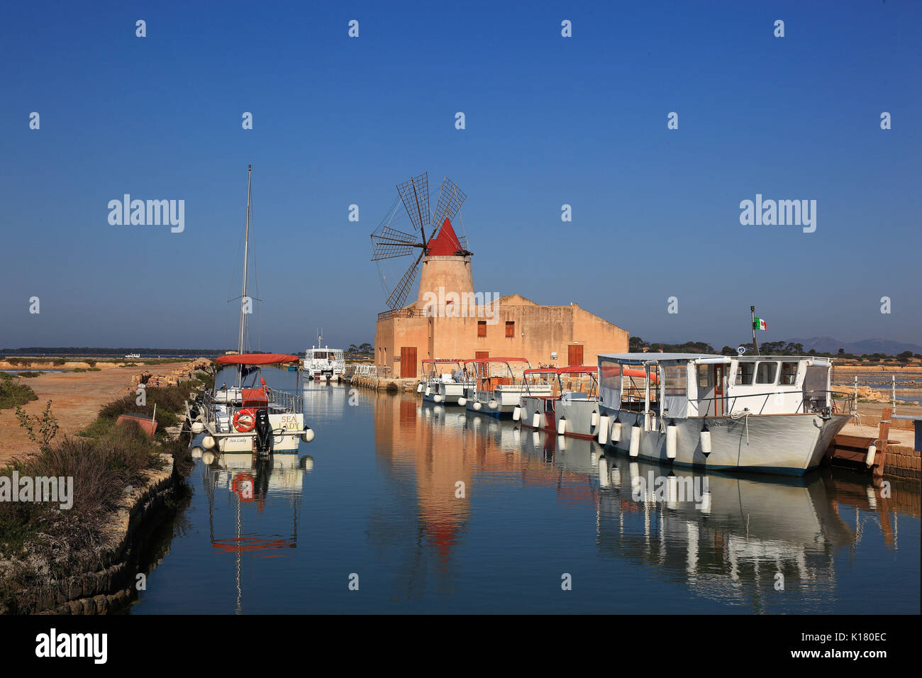 Sicilia, il mulino a vento e barche presso le Saline de Mozia vicino alla città di Marsala Foto Stock