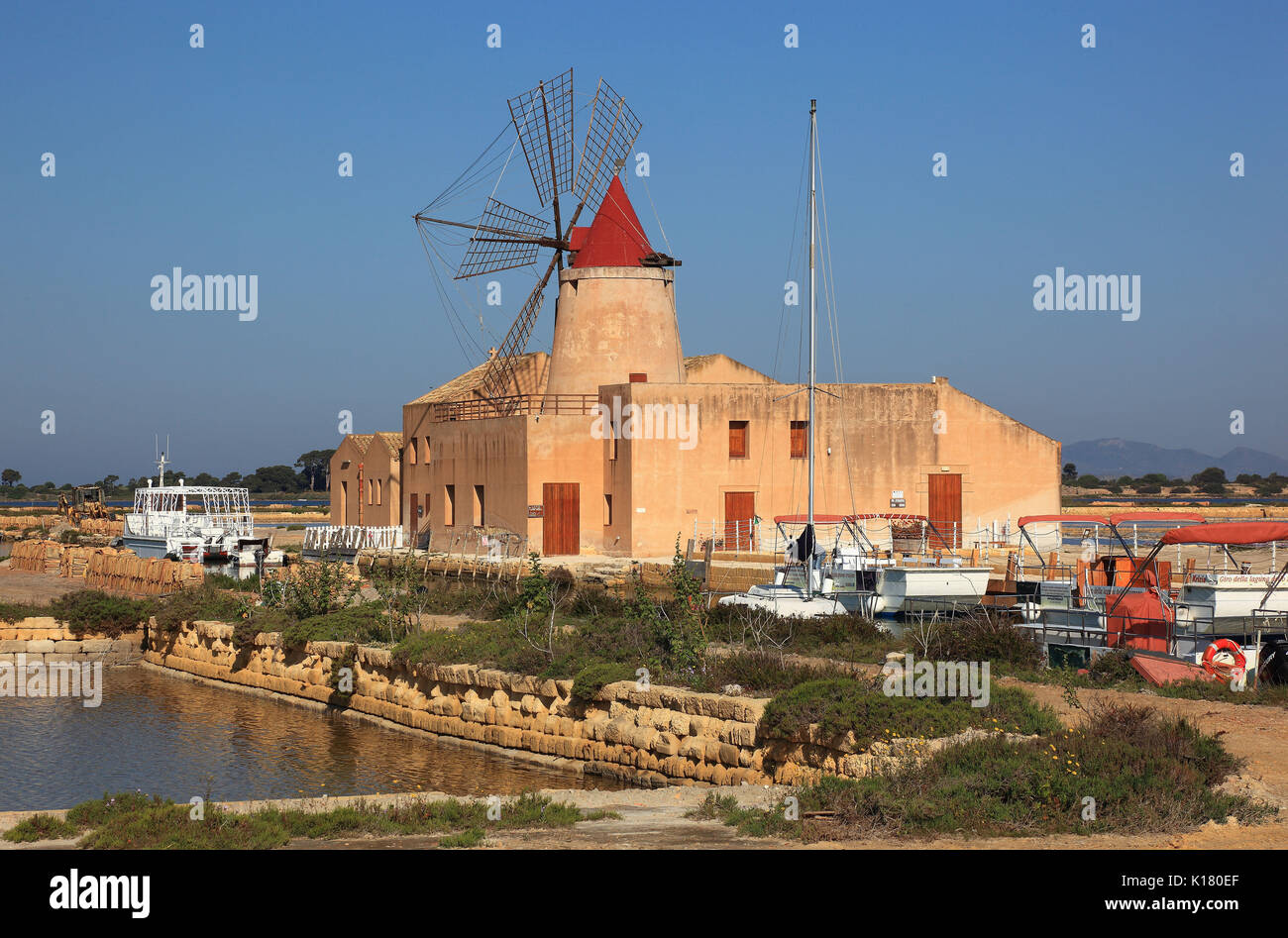Sicilia, il mulino a vento e barche presso le Saline de Mozia vicino alla città di Marsala Foto Stock