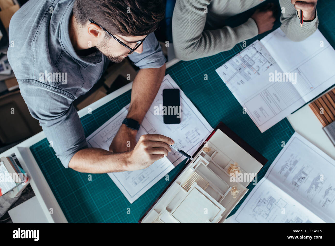 Vista dall'alto di due architetti maschile seduto in ufficio e lavorare sul progetto. Le persone creative che lavorano sulla nuova architettura modello di casa. Foto Stock