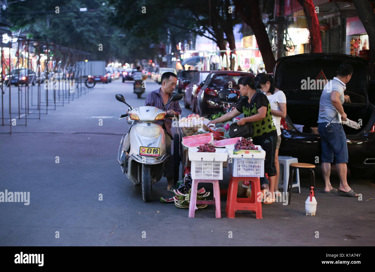 I clienti che acquistano da un frutto hawker presso un mercato notturno in città Chaozhou, Guangdong, Cina. Foto Stock