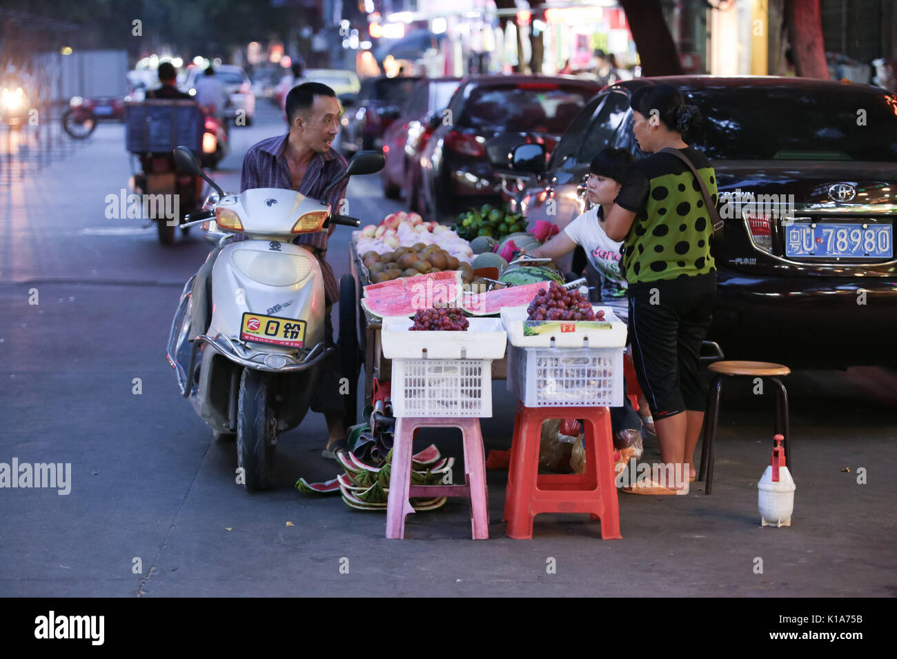 I clienti che acquistano da un frutto hawker presso un mercato notturno in città Chaozhou, Guangdong, Cina. Foto Stock