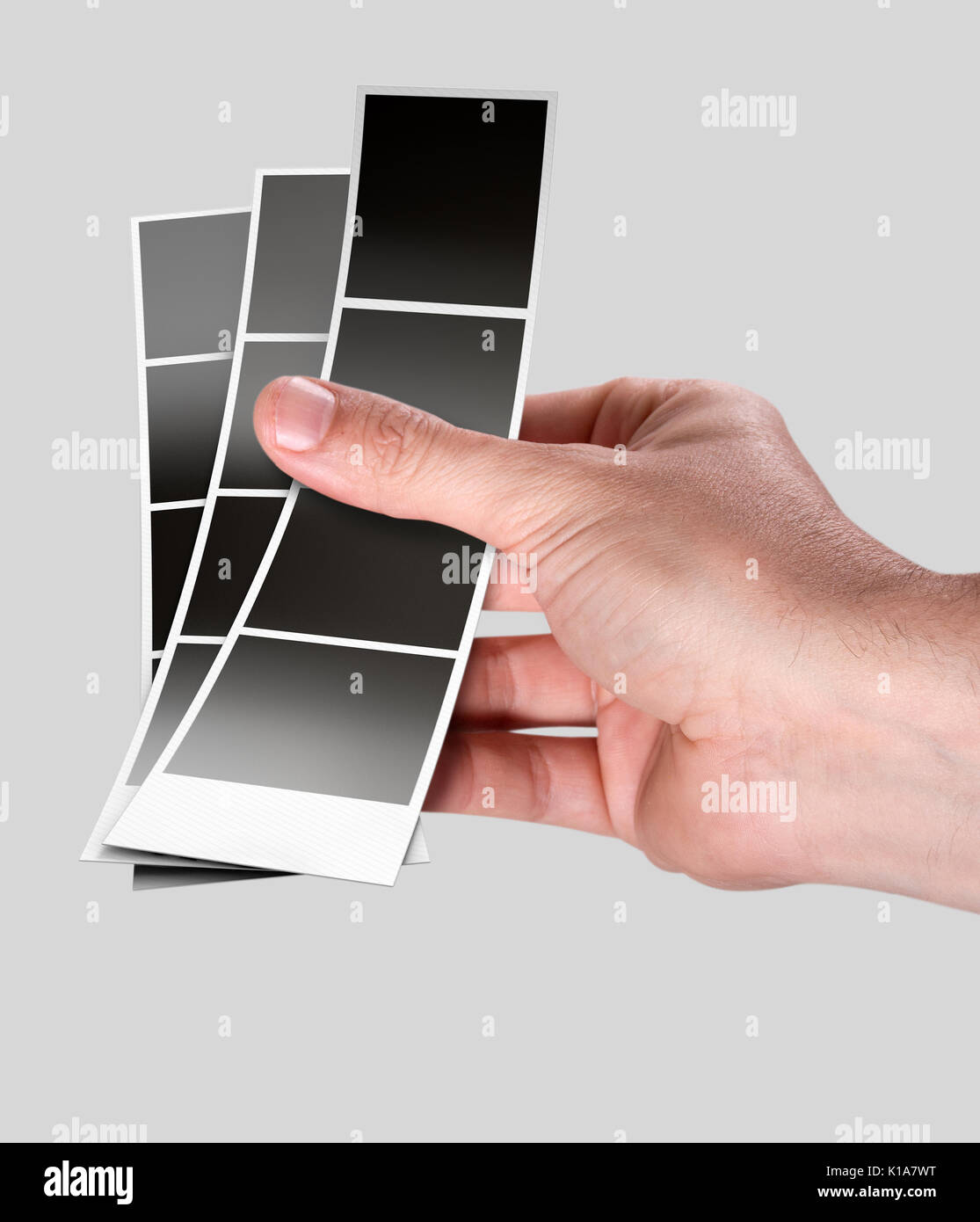 Un maschio di mano che tiene una striscia di blank foto da un istante photobooth su un isolato di sfondo per studio Foto Stock