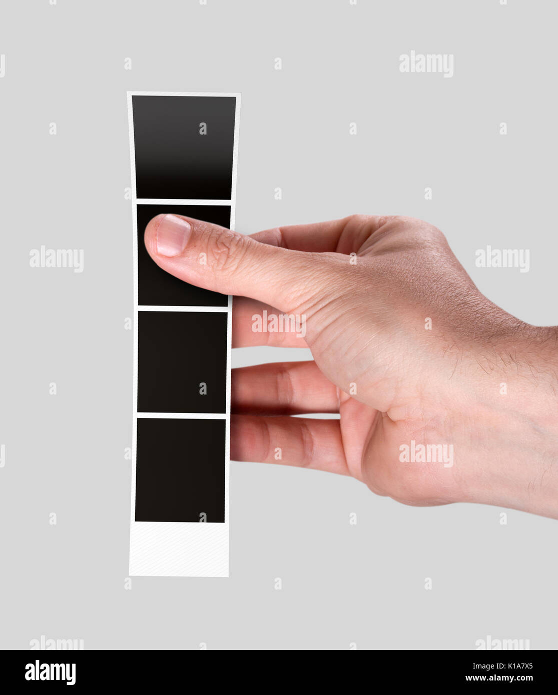 Un maschio di mano che tiene una striscia di blank foto da un istante photobooth su un isolato di sfondo per studio Foto Stock