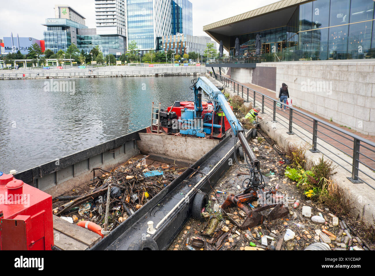 Nave di raccolta rifiuti sul canale della nave di Manchester; HIAB su una chiatta che raccoglie i detriti di plastica scartati, rifiuti, rifiuti, inquinati, inquinamento, Polistirene, e rifiuti tossici che vengono rimossi dalle rive dei canali di Salford Quays e Trafford, Greater Manchester, Inghilterra. REGNO UNITO Foto Stock