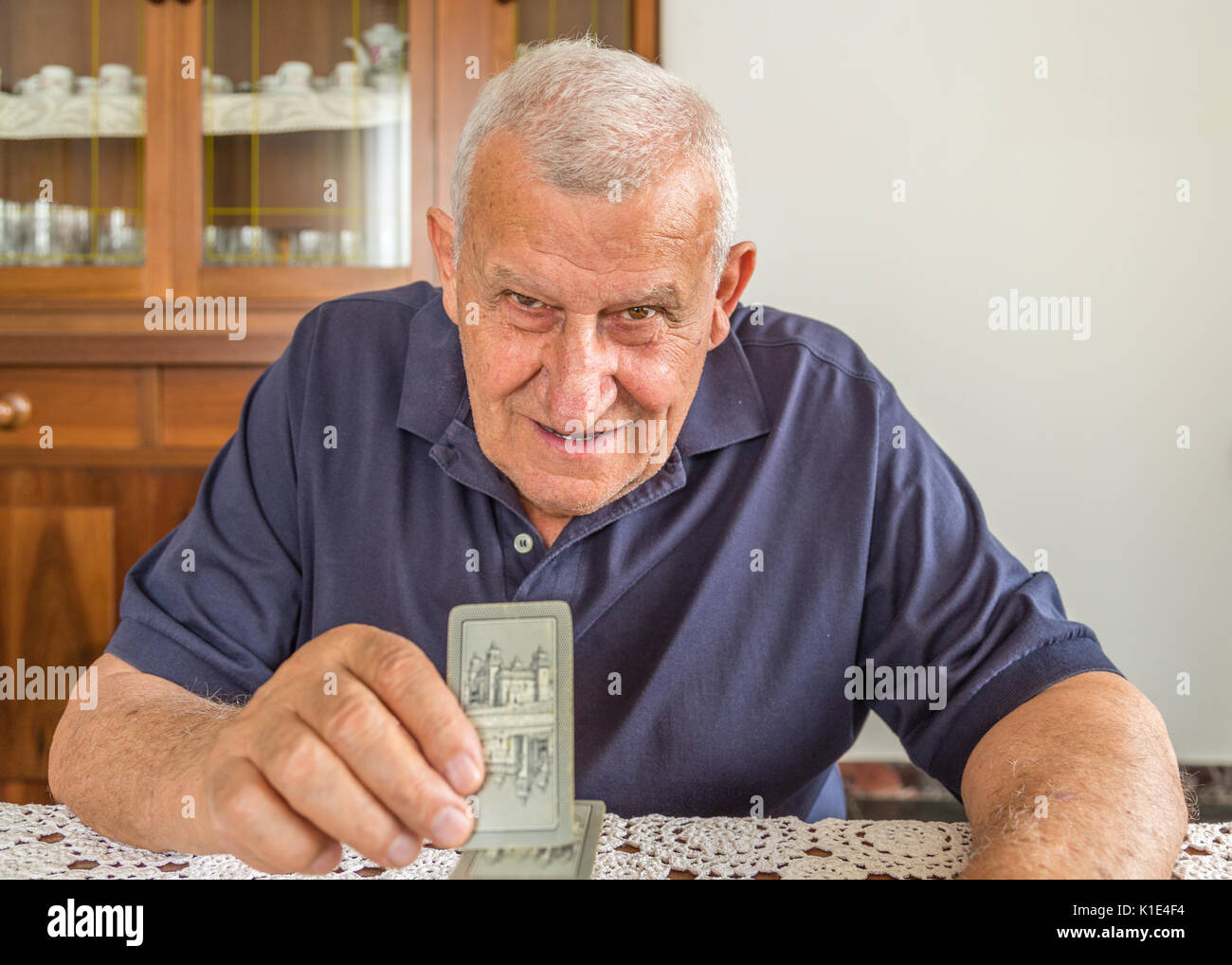 Il vecchio uomo giocando a carte dentro la sua casa Foto Stock