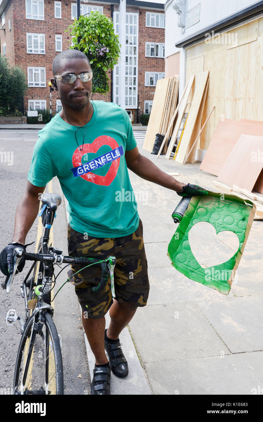 Westbourne Grove, Londra, Regno Unito. 26 Ago, 2017. Un uomo (uno dei molti ha detto) spruzzando 'Verde per Grenfell' cuore verde su i negozi sono saliti a bordo in alto lungo il percorso del carnevale. Credito: Matteo Chattle/Alamy Live News Foto Stock