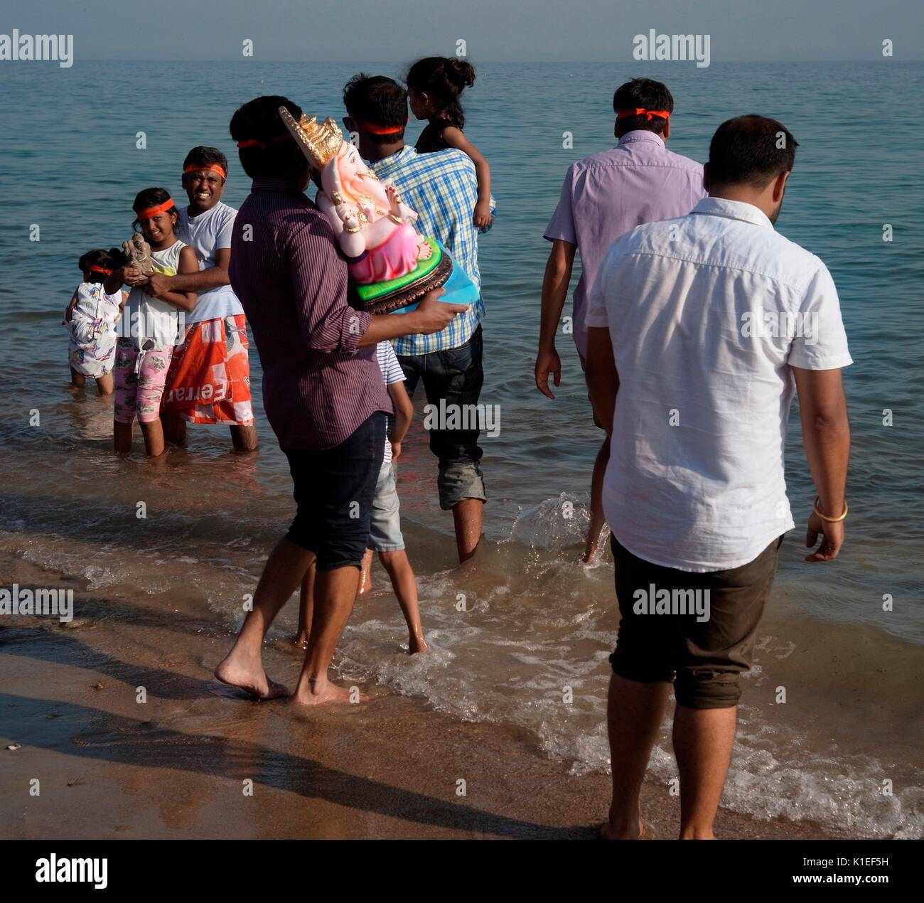 Worthing, Regno Unito. 27th ago 2017. Festeggiamo il Ganesh Festival nel Regno Unito - i membri della comunità indù locale portano un modello di Lord Ganesh lungo la spiaggia di fronte al canale inglese. Conosciuta anche come Ganesh Chaturthi, l'importante festa celebra il figlio di Lord shiva e la dea Parvati, un simbolo di saggezza, prosperità e buona fortuna. Il modello è realizzato in gesso di parigi e si scioglie in acqua di mare. Credit: Photo: Jonathan Eastland/Ajax/Alamy Live News Foto Stock