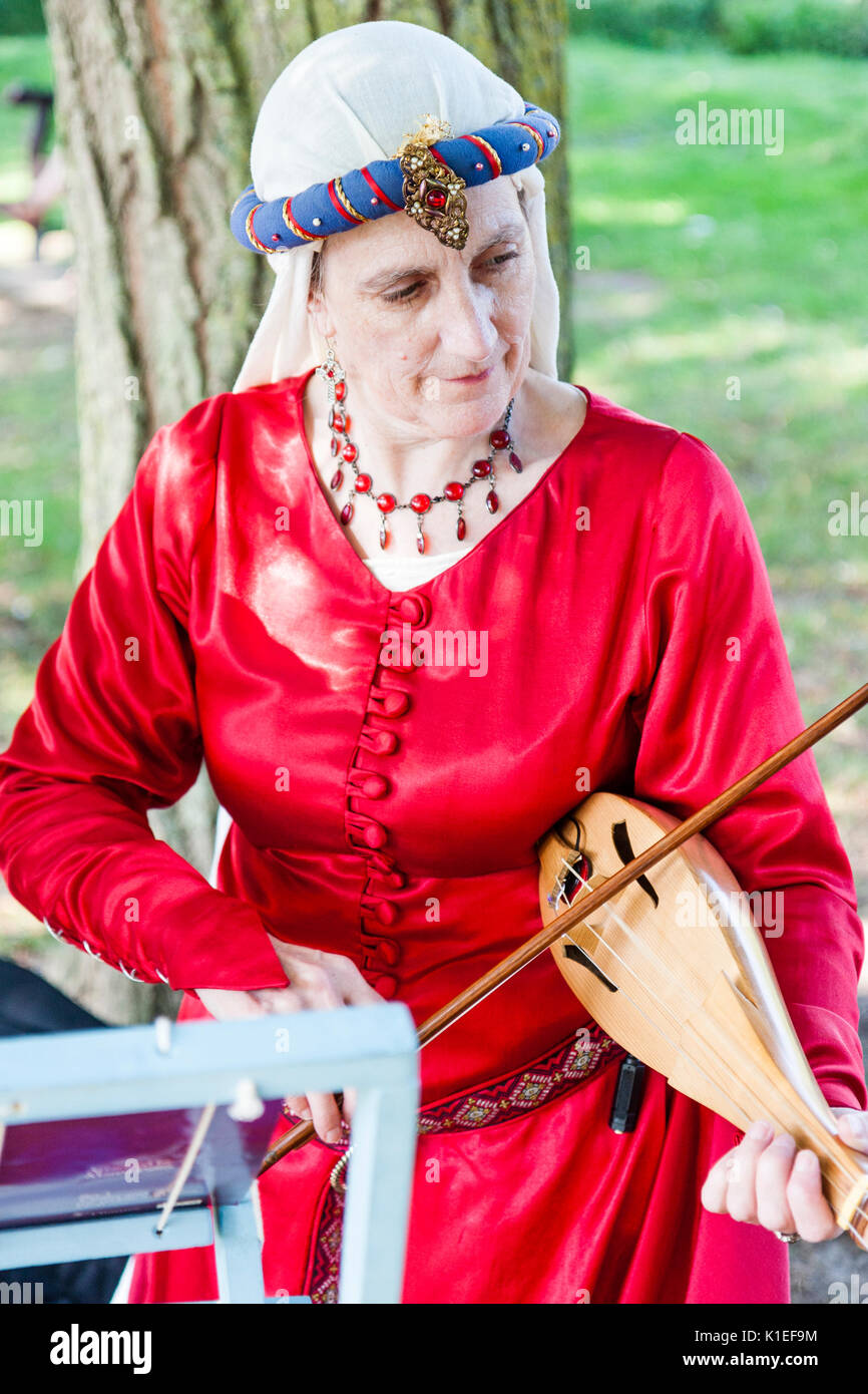 Inghilterra, sandwich. Storia viva player, donna in rosso costume medievale, in piedi sotto un albero a giocare un rebec, ribalta-runner per il violino. Foto Stock