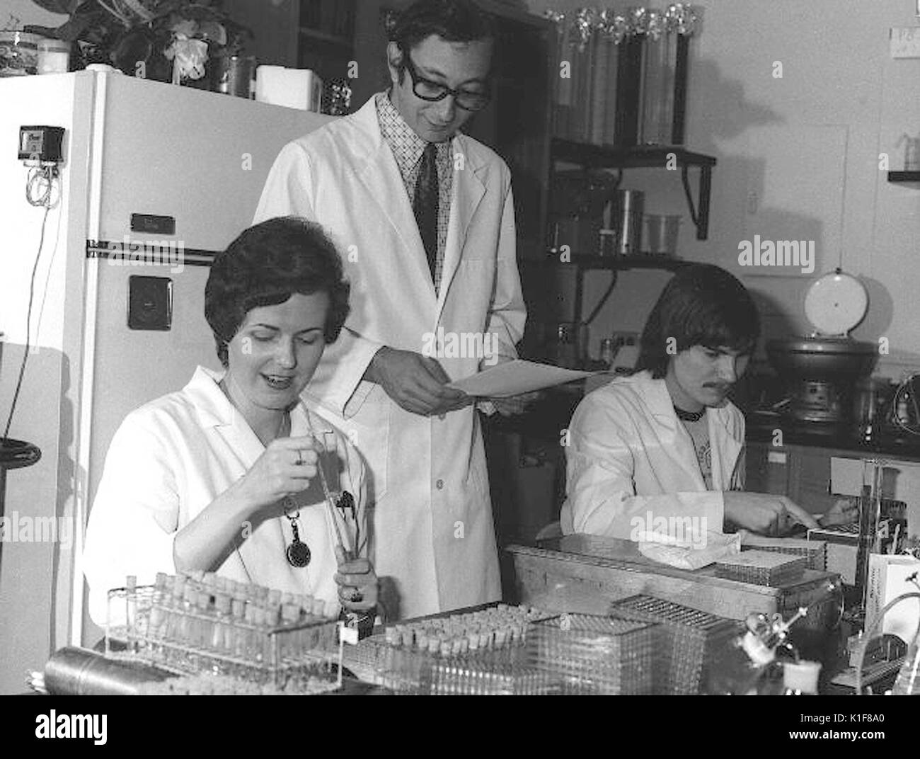 CDC Laboratorians. IMGSETINF, tecnici di laboratorio di lettura e di controllo serologies per determinare la presenza dell'influenza A/NJ/8/76 (influenza suina) e la registrazione di aumento di anticorpi al virus dell'influenza suina durante la sperimentazione del vaccino contro le prove. In piedi al centro è CDC virologist il dottor Alan Kendal. Immagine cortesia CDC/Katherine signore, 1976. Foto Stock