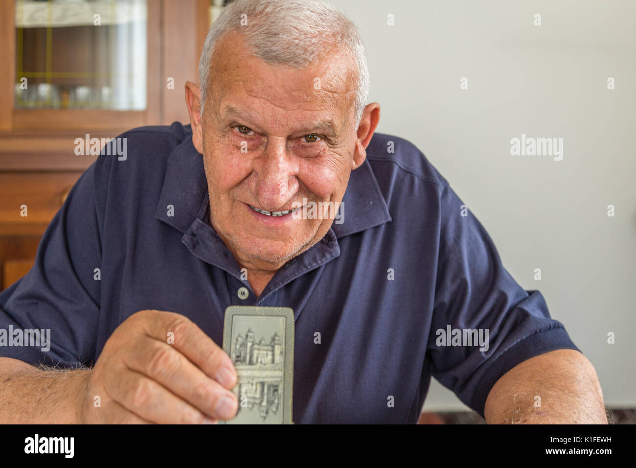 Il vecchio uomo giocando a carte dentro la sua casa Foto Stock