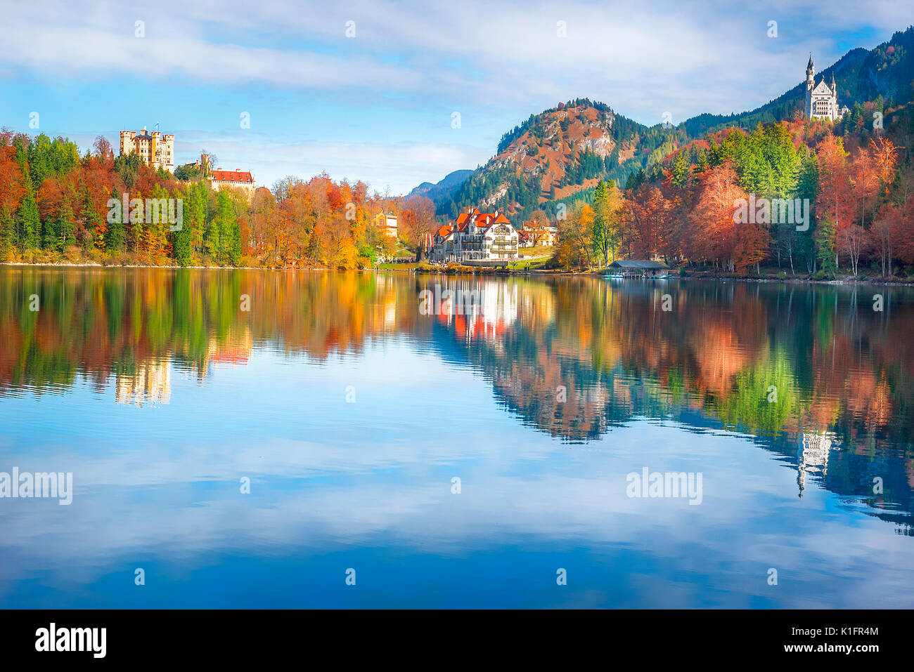 Il castello di Neuschwanstein e Hohenschwangau castello circondato da foreste in autunno colori e riflessi nel lago Alpsee Foto Stock