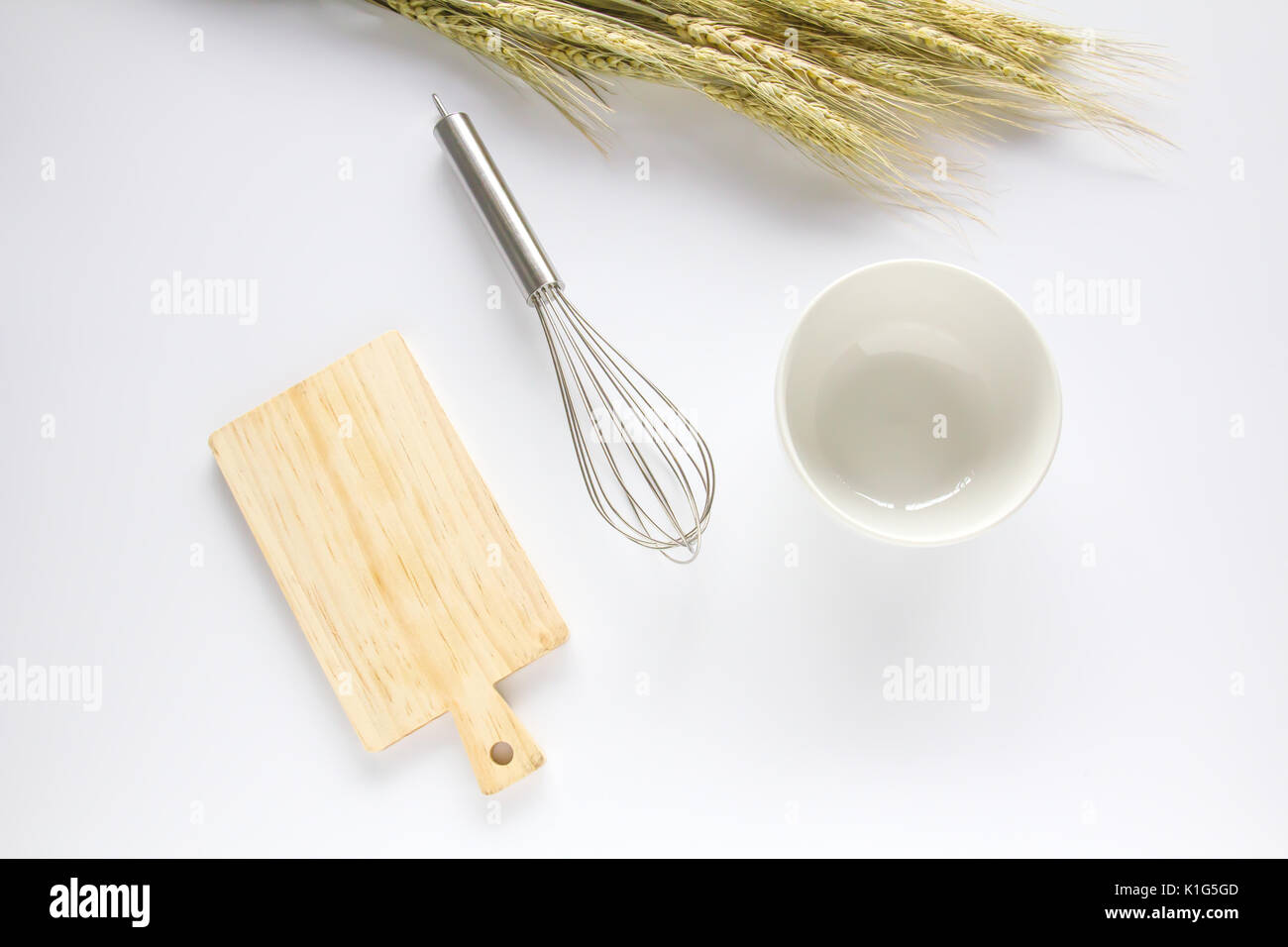 Tagliere di legno,frusta e recipiente bianco su sfondo bianco Foto Stock