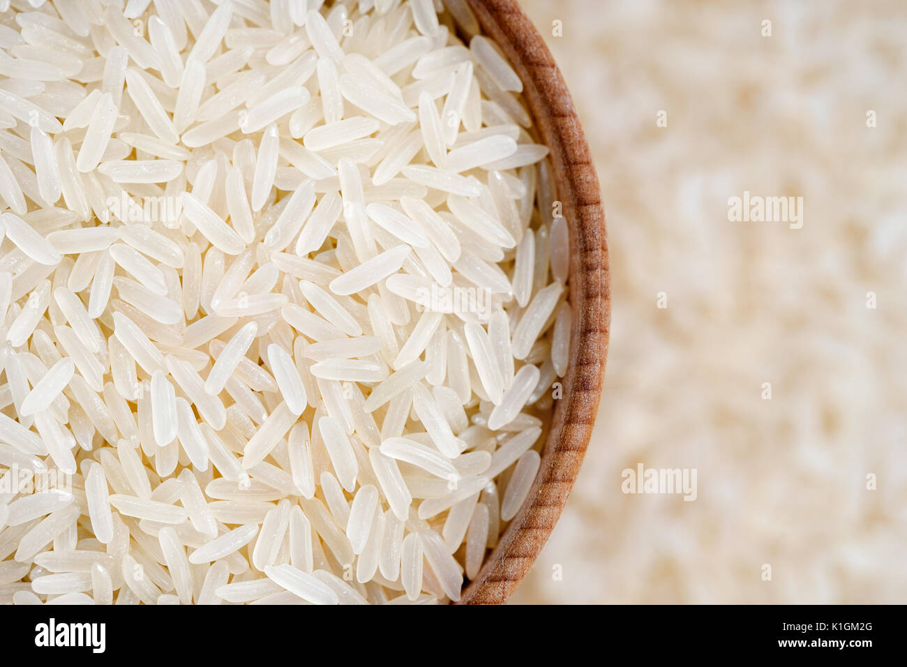 Cibo sano. Lungo il riso parboiled in ciotola di legno su sfondo sfocato. Close up. Vista superiore, dei prodotti ad alta risoluzione Foto Stock