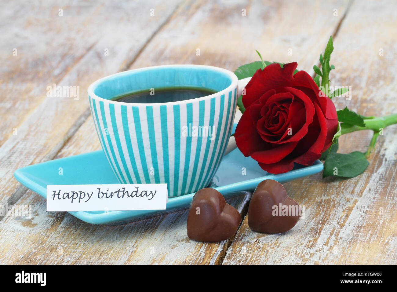 Buon compleanno card con tazza di caffè, una rosa rossa e due a forma di cuore ad cioccolatini Foto Stock