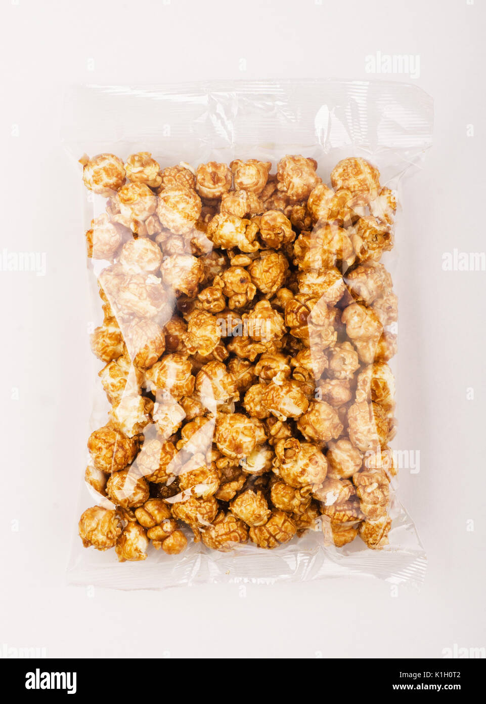 Caramello popcorn nella confezione di plastica su sfondo bianco Foto Stock