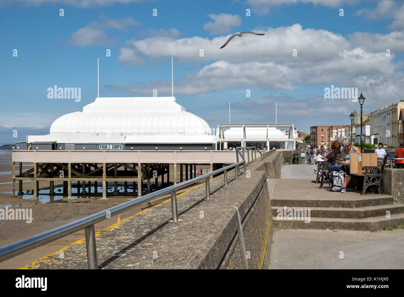 Un gabbiano volare al di sopra del lungomare, che conduce fino al Pavillion, il molo più breve in Gran Bretagna a Burnham on sea nel Somerset, Regno Unito in una giornata di sole Foto Stock