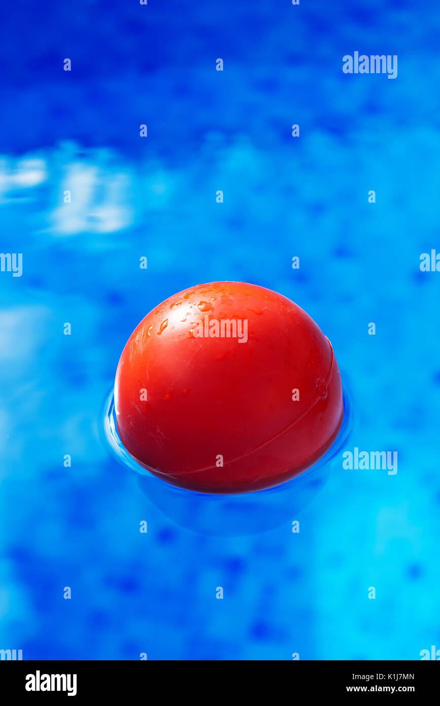 Sfera rossa galleggianti in azzurro piscina acqua, puzzle in piscina per attività estive e ricreazione Foto Stock