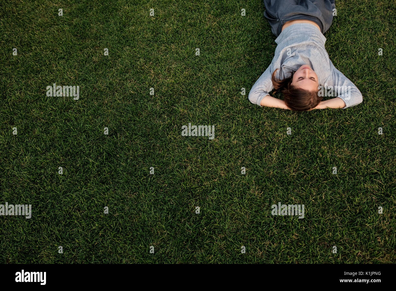 Bellissima giovane donna europea stabilisce su erba e appoggi Foto Stock